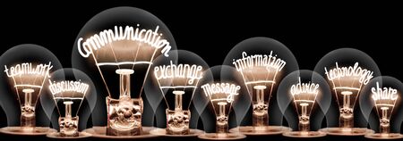 Photo of light bulbs with shining fibers in a shape of Communication, Teamwork, Exchange and Technology concept related words isolated on black backgroundの写真素材