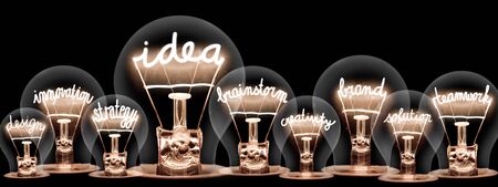 Photo of light bulbs with shining fibers in a shape of Idea, Brand, Brainstorm, Innovation and Teamwork concept related words isolated on black backgroundの写真素材