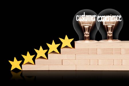 Photo of five yellow stars and light bulbs with shining fibers in a shape of Customer Experience concept words isolated on black background.の写真素材