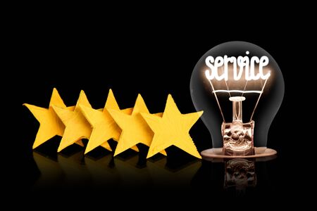 Photo of five yellow stars and light bulb with shining fiber in a shape of Service concept word isolated on black background.の写真素材