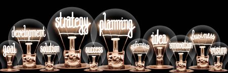 Group of light bulbs group with shining fibers in a shape of Strategy Planning, Idea, Goal and Solution concept related words isolated on black backgroundの写真素材