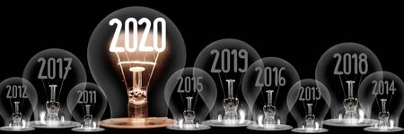 Group of shining and dimmed light bulbs with fibers in 2020, 2019, 2018 isolated on black background; New Year conceptの写真素材