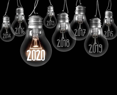 Group of shining and dimmed light bulbs with fibers in 2020, 2019, 2018 isolated on black background. New Year concept.の写真素材