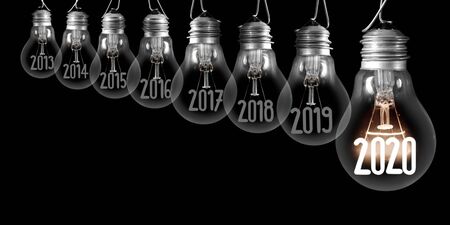 Group of shining and dimmed light bulbs with fibers in 2020, 2019, 2018 isolated on black background. New Year concept.の写真素材