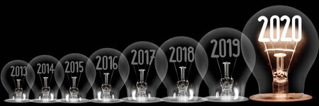 Group of shining and dimmed light bulbs with fibers in 2020, 2019, 2018  isolated on black background. New Year concept.の写真素材