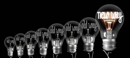 Large group of shining and dimmed light bulbs with fibers in a shape of New and Old Way words isolated on black background. Concept of Innovation, Development and Successの写真素材
