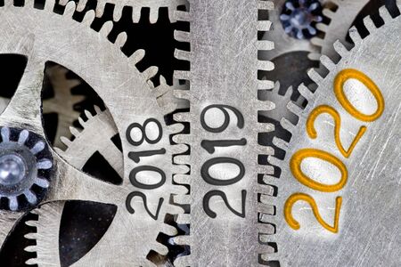 Photo of tooth wheel mechanism with numbers 2020, 2019 and 2018 imprinted on metal surface. New Year, Future, Past and Time concept.の写真素材