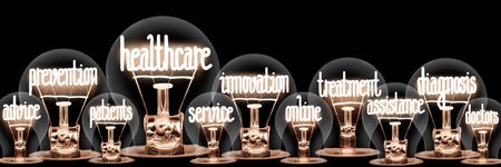 Photo of light bulb group with shining fibers in a shape of Healthcare, Prevention, Innovation and Treatment concept related words isolated on black backgroundの写真素材