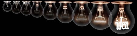 Group of light bulbs going from dark one to a shining one with fiber in Idea shape isolated on black background. Concept of Thinking, Success and Creativity.の写真素材
