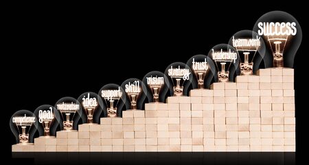 Light bulbs with shining fibers in a shape of Success, Teamwork, Support and Trust concept related words on wooden block ladder isolated on black background.の写真素材