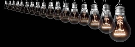 Group of light bulbs going from dark one to a shining one isolated on black background. Concept of Idea, Thinking, Success and Creativity.の写真素材