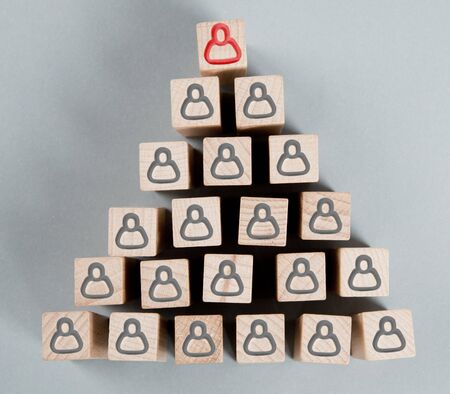 Wooden blocks with red and black human symbols in a triangular shape. Management, Leadership and...