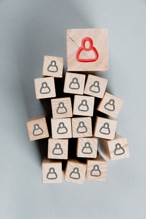 Wooden blocks with red and black human symbols being hold with human hand. Management, Leadership and Teamwork concept.の写真素材