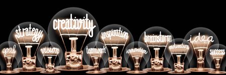 Photo of light bulbs with shining fibers in a shape of Creativity, Strategy, Inspiration, Brainstorm and Idea concept related words isolated on black backgroundの写真素材