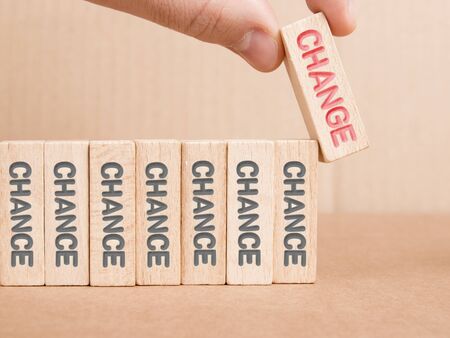 Wooden blocks with Chance and Change imprinted, one of them hold by a human hand.の写真素材