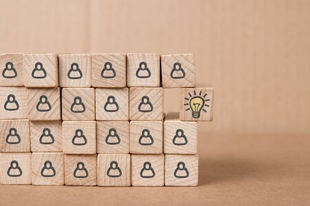 Wooden blocks with human icons and one of them separated with light bulb symbol imprinted.の写真素材