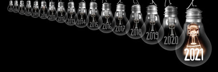 Horizontal group of shining light bulb with fiber in a shape of New Year 2021 and dimmed light bulbs with years passed isolated on black background.の写真素材
