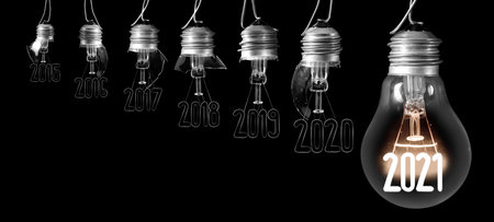 Horizontal group of shining light bulb with fiber in a shape of New Year 2021 and dimmed light bulbs with years passed isolated on black background.の写真素材