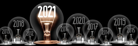 Horizontal group of shining light bulb with fiber in a shape of New Year 2021 and dimmed light bulbs with years passed isolated on black background.の写真素材