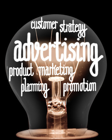 Single light bulb with shining fibers in a shape of Advertising, Strategy, Customer and Marketing concept related words isolated on black backgroundの写真素材
