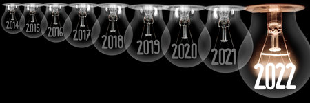 Horizontal group of shining light bulb with fiber in a shape of New Year 2022 and dark light bulbs with years passed isolated on black background.の写真素材