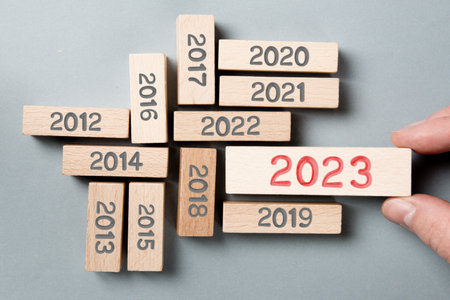 Photo of wooden blocks hold by a human hand with gray numbers and red number 2023 imprinted on wooden surface. New Year concept.の写真素材