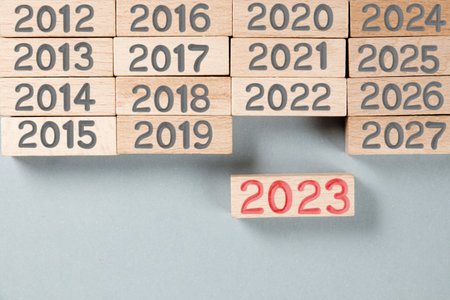 Photo of wooden blocks with gray numbers and red number 2023 imprinted on wooden surface. New Year concept.の写真素材