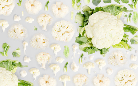 Abstract background made of Cauliflower vegetable pieces, slices and leaves isolated on gray background.の写真素材