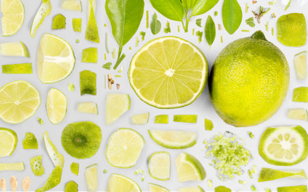 Abstract background made of Lime fruit pieces, slices and leaves isolated on gray background.の写真素材
