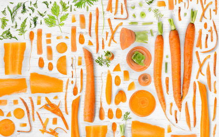 Abstract background made of Carrot vegetable pieces, slices and leaves on wooden background.の写真素材