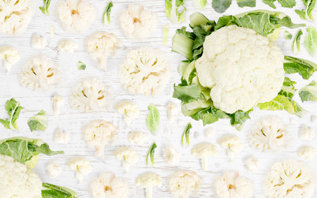 Abstract background made of Cauliflower vegetable pieces, slices and leaves on wooden background.の写真素材