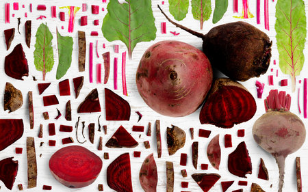 Abstract background made of Red Beet vegetable pieces, slices and leaves on wooden background.の写真素材