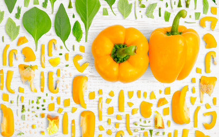 Abstract background made of Yellow Bell Pepper vegetable pieces, slices and leaves on wooden background.の写真素材