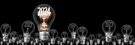 Horizontal group of shining light bulbs with fiber in a shape of New Year 2024 and dark light bulbs with years passed isolated on black background.の写真素材