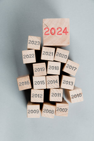 Photo of wooden block group with gray numbers of past years and one of them standing out with red number 2024 imprinted on wooden surface. New Year concept.の写真素材