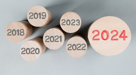 Photo of round wooden block rows with gray numbers of passed years and one of them standing out with red number 2024 imprinted on wooden surface. New Year concept.の写真素材