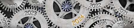 Photo of tooth wheel mechanism with numbers 2024, 2023, 2022 imprinted on metal surface. New Year...