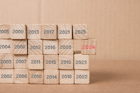 Photo of wooden block rows with gray numbers of past years and one of them standing out with red number 2024 imprinted on wooden surface. New Year concept.の写真素材