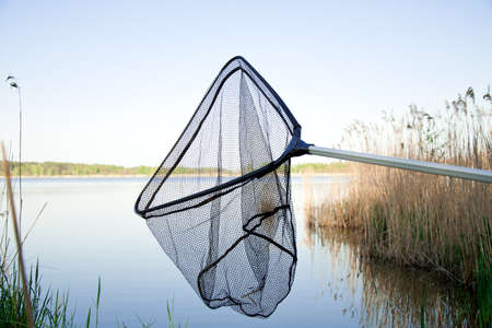 Landing net on the lake with blue sky outsideの写真素材