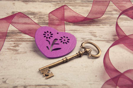 violet wooden heart on wooden desk with key and ribbonの写真素材