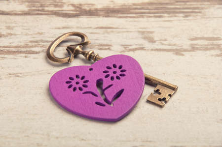 violet wooden heart on wooden desk with key and ribbonの写真素材