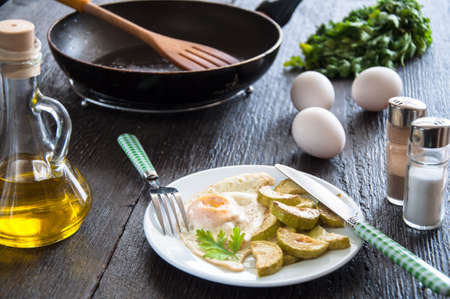 fried eggs and chopped zucchini with parsleyの写真素材