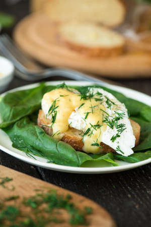Poached egg on a piece of bread with spinach on the tableの写真素材