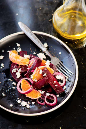 Salad with beetroot and orange, onions on the black plateの写真素材