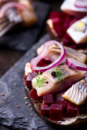 Sandwiches with herring and beetroot on a slate black plateの写真素材