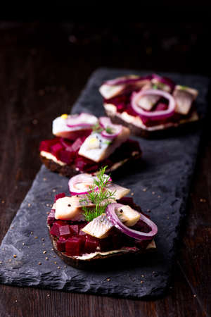 Sandwiches with herring and beetroot on a slate black plateの写真素材