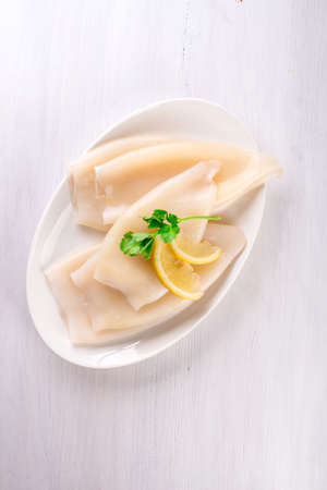 Raw squid and ingredients on the white plateの写真素材