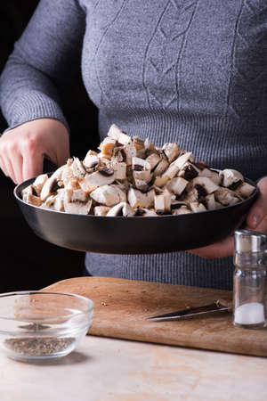 female hands hold fresh mushrooms in the panの写真素材