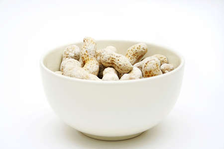 a bowl with salted peanuts on white surface to be used as backgroundの写真素材