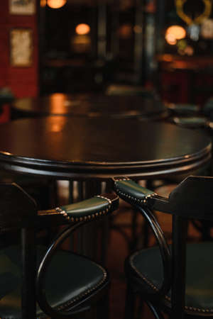 Vintage barrel table with two vintage high chairs, dark interior and dark furniture.